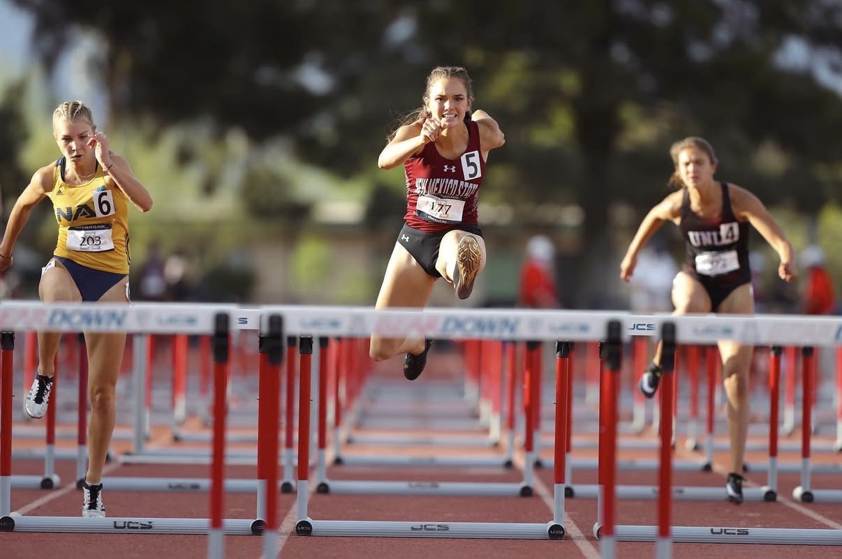 Israel Swanson clearing a hurdle mid-race for New Mexico State